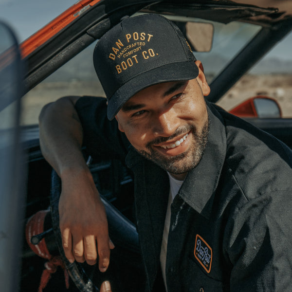Men's model wearing black Dan Post Boot Co trucker hat