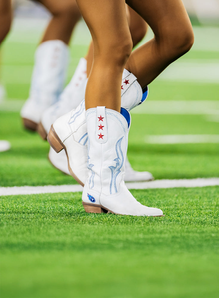 White cowboy boots with star design on a grass field